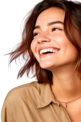 Mulher de pele parda, de cabelos curtos, lisos e castanhos, sorrindo. Usa uma camisa na cor marrom