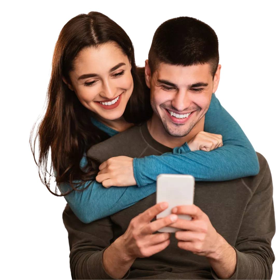 Mulher de pele retita, de cabelos cacheados e escuros, usando um óculo de armação redonda, sorrindo. Usa um blazer de cor bege e segura um celular com as mãos