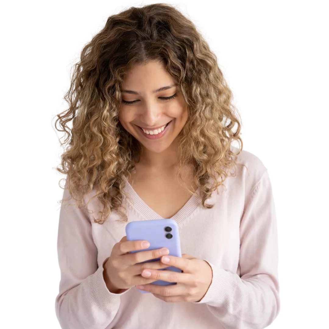 Mulher de pele retita, de cabelos cacheados e escuros, usando um óculo de armação redonda, sorrindo. Usa um blazer de cor bege e segura um celular com as mãos